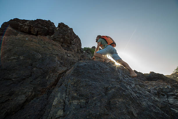 istock Young man climbs steep rock, towards sunlight 600058468