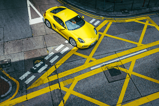 Hong Kong, China - October 31, 2015: A yellow Porsche car driving down a street in Mongkok district. Hong Kong is one of Asia's wealthiest cities.