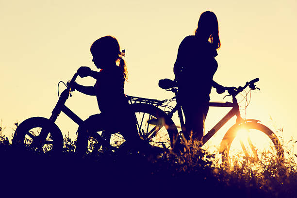 istock mother and little daughter riding bikes at sunset 600063314