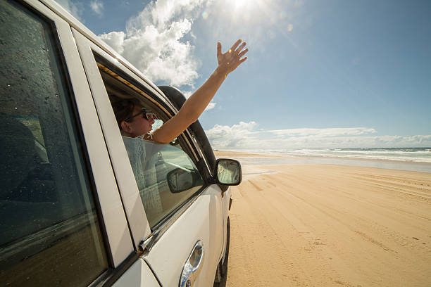 istock Young woman in a car driving on sandy beach 600064348