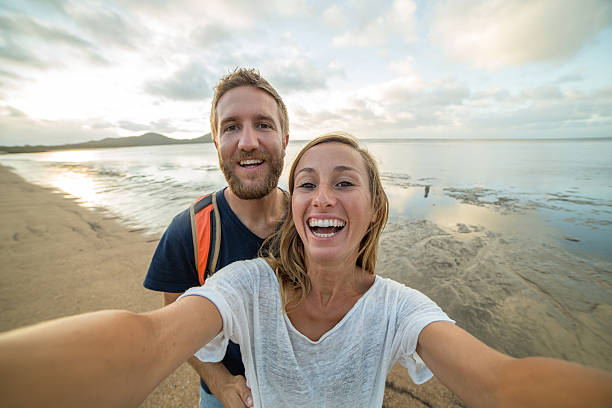 istock Cheerful young couple on the beach take a selfie portrait 600065924