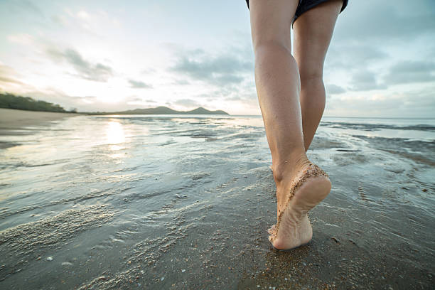istock Close up on barefoot walking on the beach at sunrise 600067494