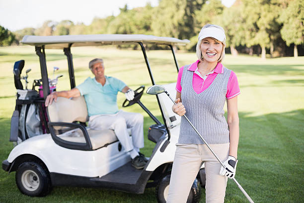 istock Smiling mature woman standing by man in golf buggy 600068562