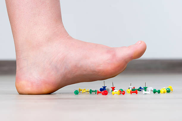 Female foot above colored pushpin stock photo