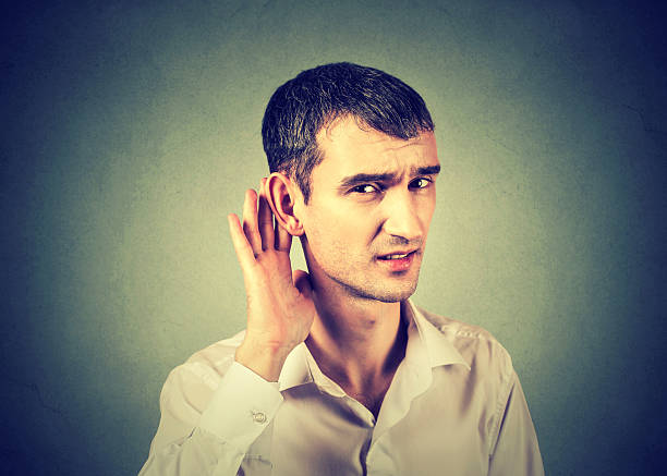 istock hard of hearing man hand on ear asking speak up 600069328