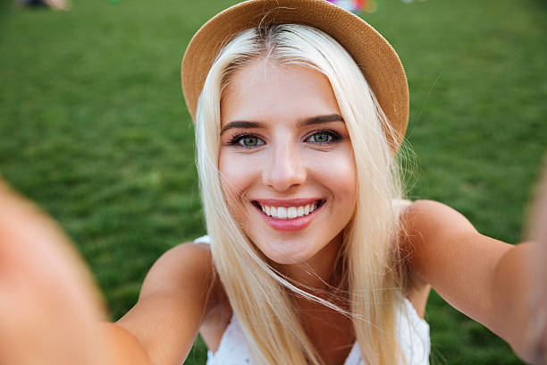 istock Young smiling cheerful blonde girl in hat making selfie 600069656