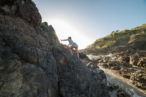 istock Young woman climbs steep rock, towards sunlight 600071428