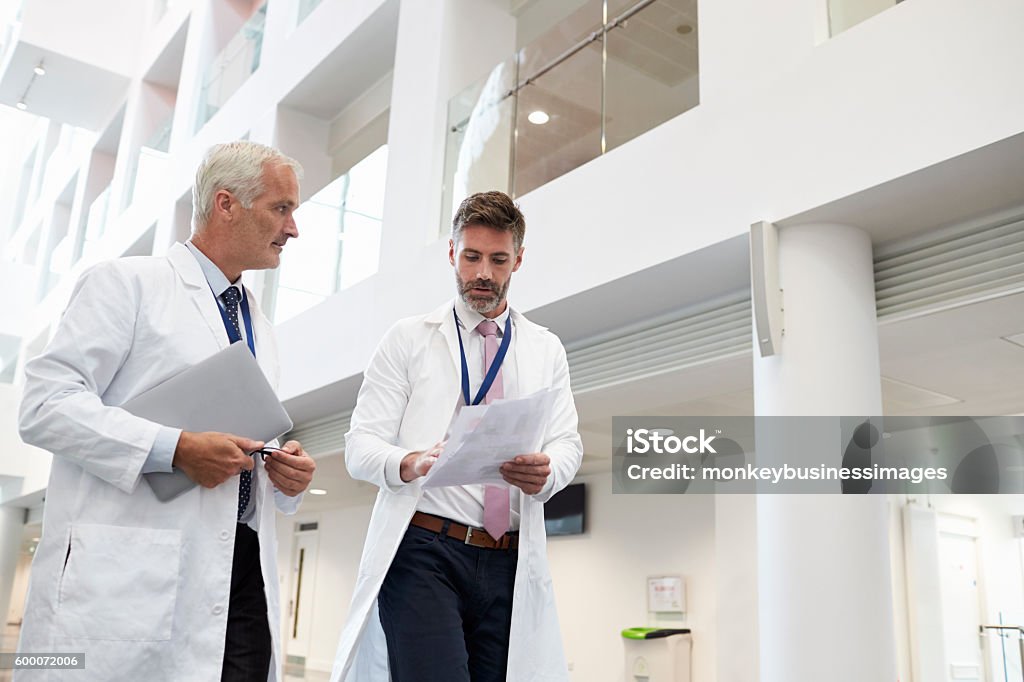 Zwei Ärzte sprechen, während sie durch modernes Krankenhaus gehen - Lizenzfrei Arzt Stock-Foto