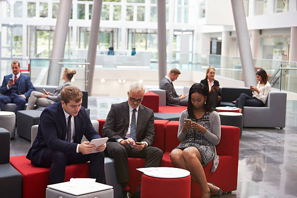 istock Businesspeople Using Digital Devices In Busy Office Lobby 600072660
