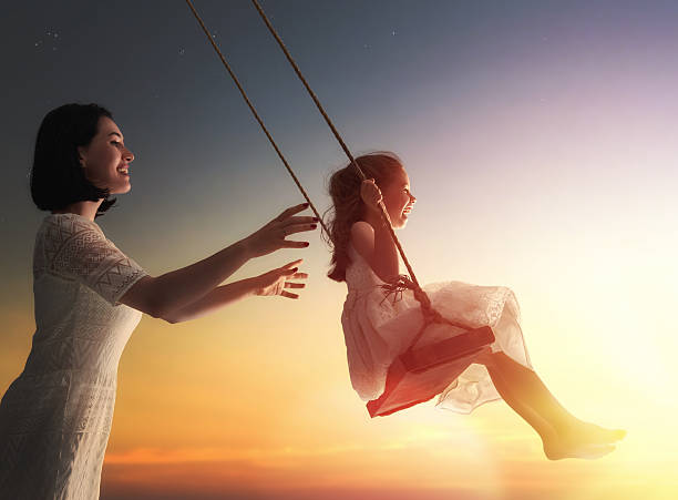 istock mother and  daughter swinging on swings 600073384