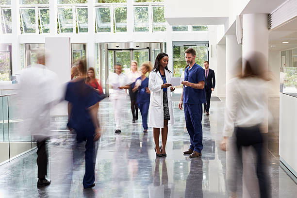 staff in busy lobby area of modern hospital - ziekenhuis stockfoto's en -beelden