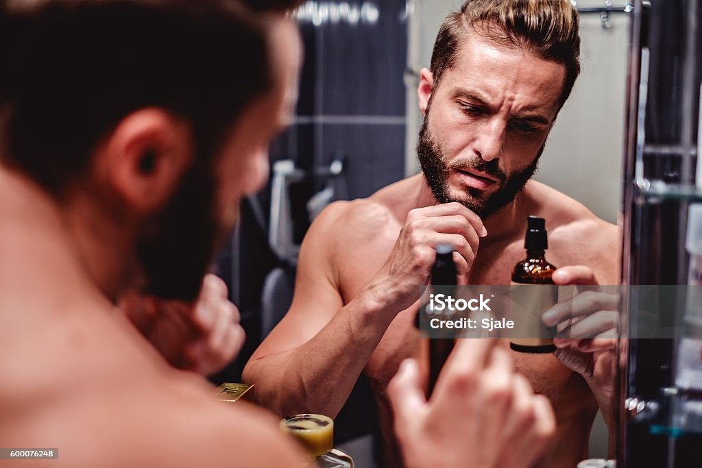 Hipster man holding bottle in the bathroom Hipster shirtless man holding bottle in the bathroom Men Stock Photo