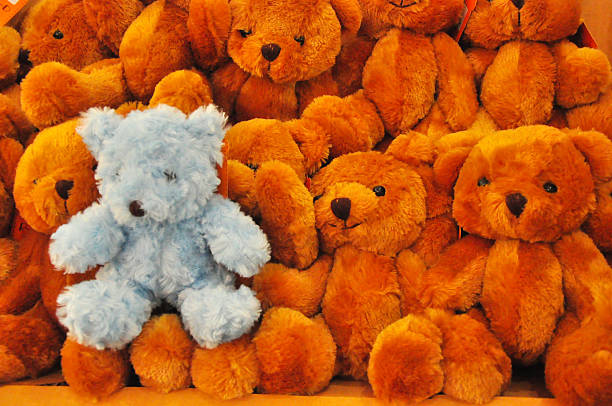 Blue teddy bear sitting on a brown teddy bear masses.
