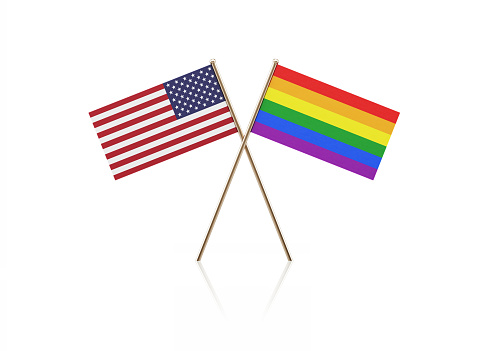 Tiny American and LGBT flag pair on gold sticks. Flag pair is standing on a reflective surface. Isolated on white background. With clipping path.