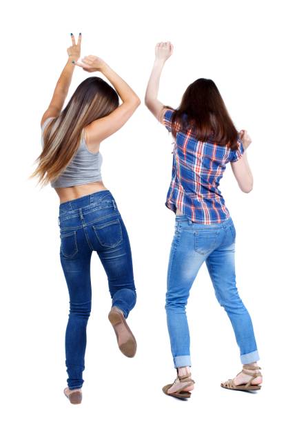 Back view of two dancing young women. Back view of two dancing young women. Dance party. girls teens dance, enjoy and express positive emotions and having fun. Two young girls in jeans dancing pics of girls buttocks stock pictures, royalty-free photos & images