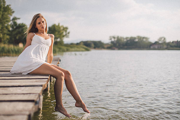 Beautiful young woman relaxing on jetty above lake