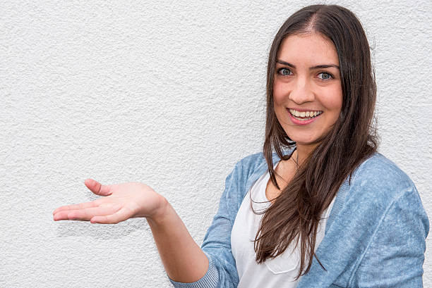 istock beautiful young woman holding up her hand before white wall 600088860