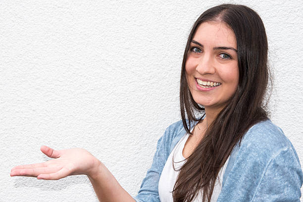 istock beautiful young woman holding up her hand before white wall 600089094