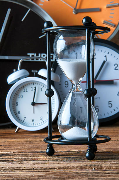 istock Hourglass and ticking clocks on old wooden table 600090002