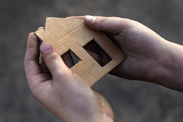 istock homeless boy holding a cardboard house 600131858