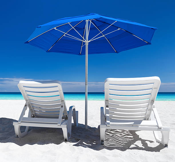 istock Caribbean beach with blue sun umbrellas and white beds 600133936