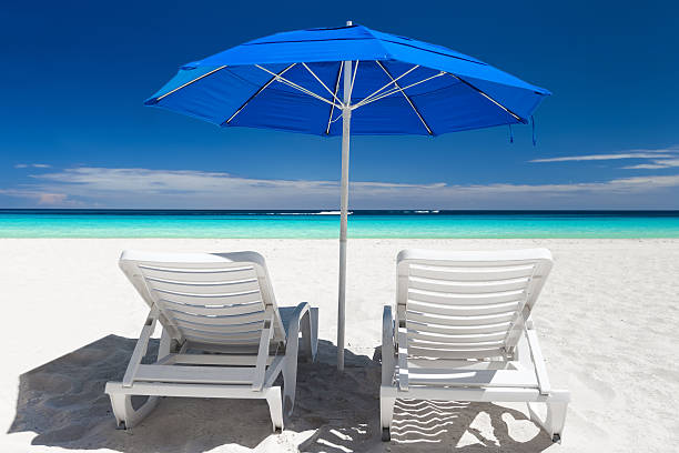 istock Caribbean beach with blue sun umbrellas and white beds 600134300