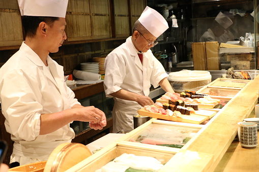 Tokyo, Japan - June 21, 2015: Sushi chefs preparing Sushi plate at small restaurant in Tsukiji Fish Market
