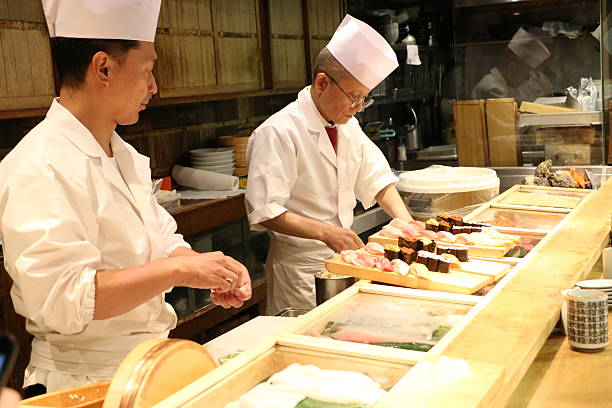 Sushi Chefs Tokyo, Japan - June 21, 2015: Sushi chefs preparing Sushi plate at small restaurant in Tsukiji Fish Market japanese chef stock pictures, royalty-free photos & images