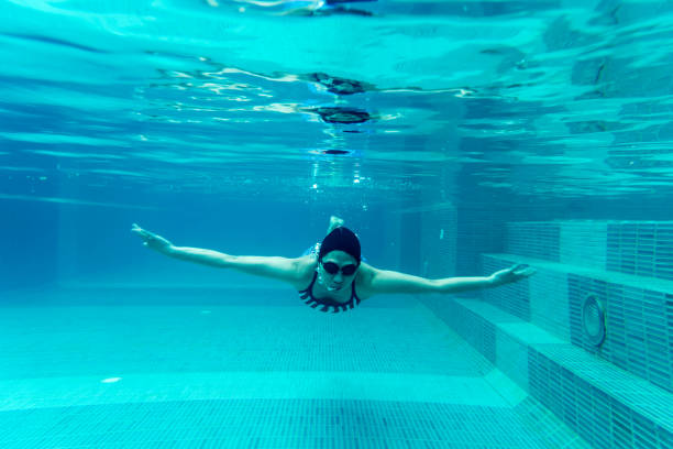 istock girl swimmimg underwater in pool 600142098