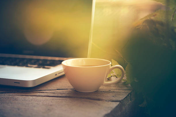 istock white Cup of coffee and laptop on wooden table. 600145468