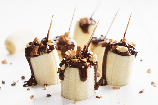 chocolate banana bites with chopped toasted almond topping on white wooden background