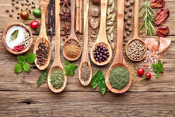 Spices with fresh herbs on a wooden background