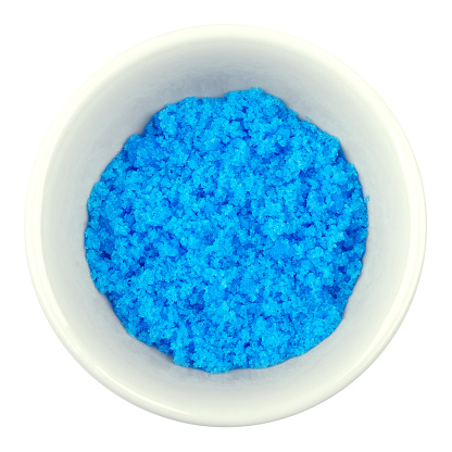 Cupric sulfate in porcelain bowl over white. Bright blue copper sulfate CuSO4, also blue vitriol or bluestone. Salt, used as algicide in swimming pools, for fireworks and in schools to grow crystals.