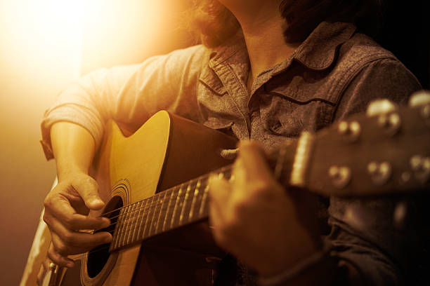 istock woman's hands playing acoustic guitar 600155782
