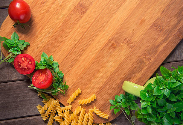 Tomatoes, basil and pasta on wood table. View from above with copy space