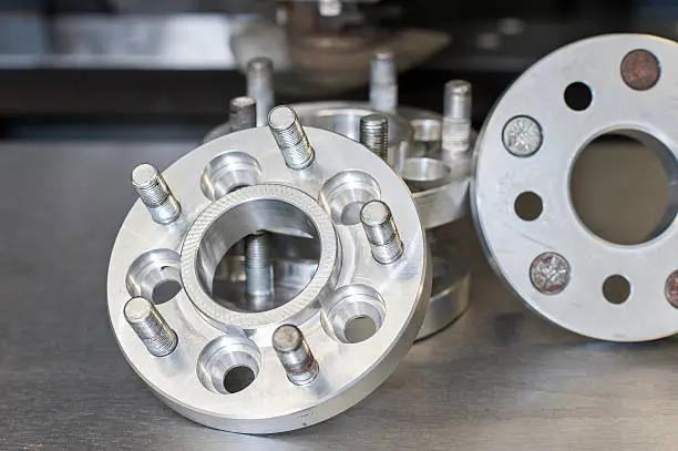 Photo of new metal mold of wheel spacers with bolts. CNC industry
