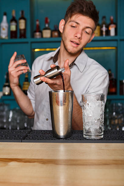 istock Young handsome barman pouring cocktail drink into glass 600162574