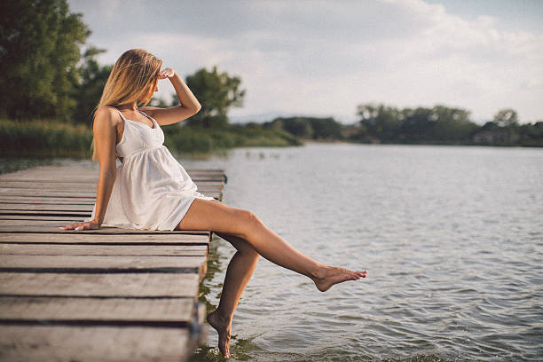 Close up of woman in swimwear sitting on pier by the sea during summer day. Copy space.