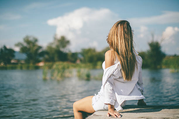 istock Young woman relaxing on lake pier 600165336