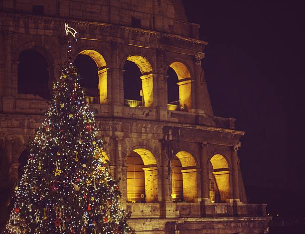 The landmark of Rome: Flavian Amphitheater, or the Colosseum, at night, with a christmas tree in front of it