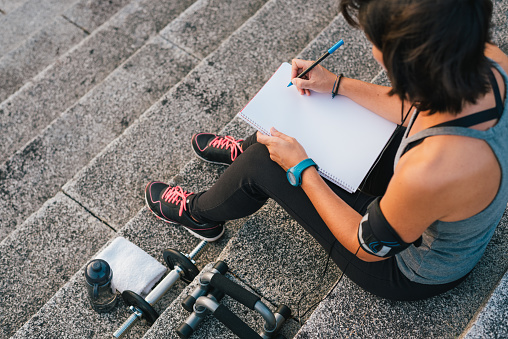 Atleta femenina urbana centrada en sus objetivos escribiendo en el bloc de notas photo