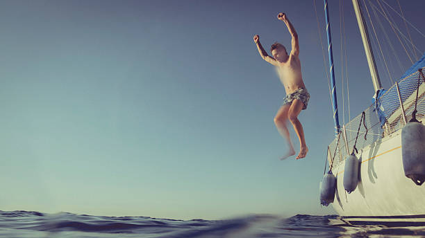 istock Man jumping and diving from a yacht sailboat 600166232