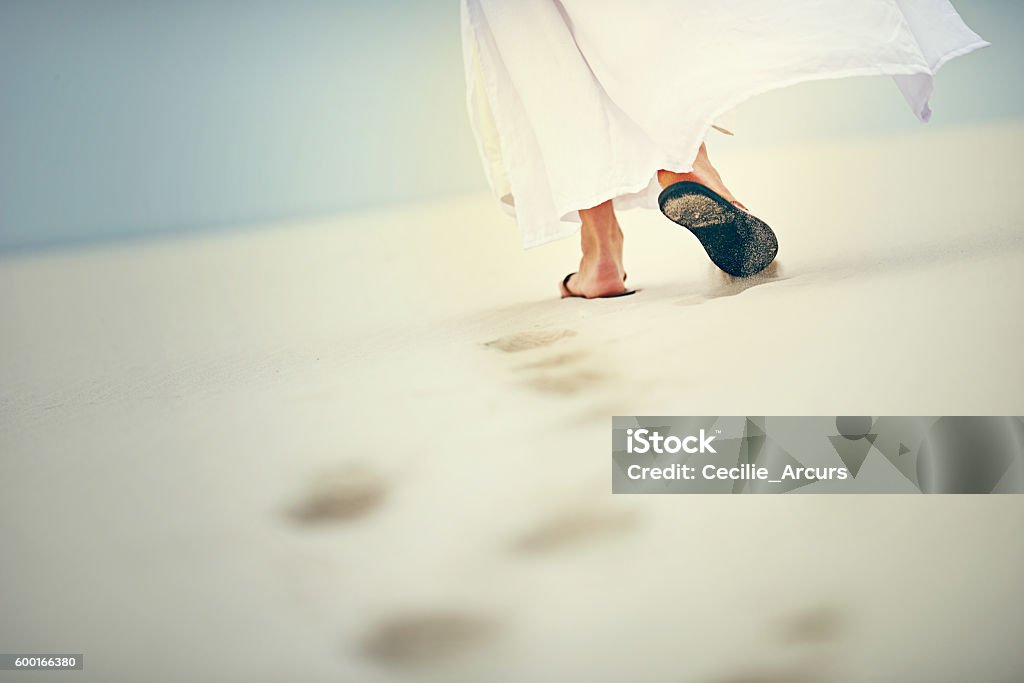 It is in difficult times that He carries you Shot of Jesus walking in a sandy landscape Jesus Christ Stock Photo