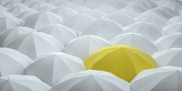 Unique yellow umbrella among many white ones. Standing out from crowd, individuality and difference concept.Unique yellow umbrella among many dark ones. Standing out from crowd, individuality and difference concept.