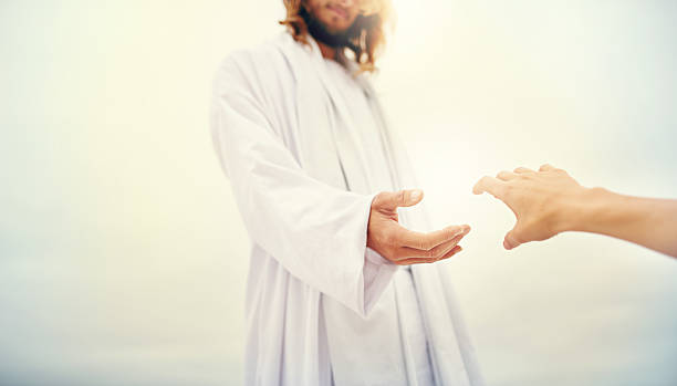 Come, you who are blessed by the Lord Shot of Jesus standing with his hand outstretched toward a follower on a bare landscape jesus christ stock pictures, royalty-free photos & images