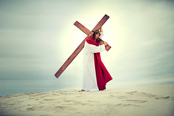 Shot of Jesus carrying his cross across a bare landscape