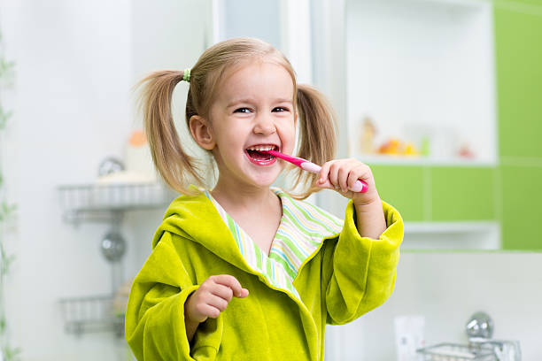 Smiling little girl brushing teeth in bathroom