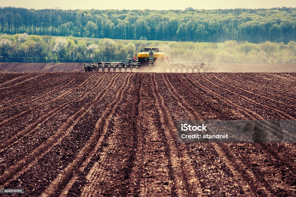 Tractor plowing farm field in preparation for spring planting. Agriculture Stock Photo