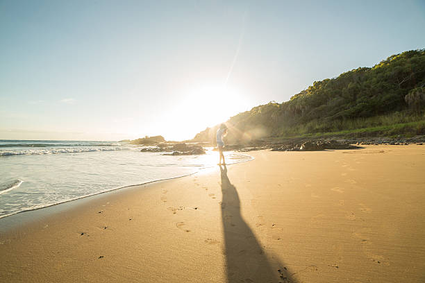 istock Distant person arms outstreched on beach at sunrise 600175660