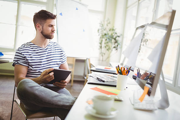 istock Businessman holding digital tablet while sitting in office 600177106